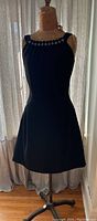 Full view of the sleeveless black dress on a dress form, showing overall silhouette and shape.