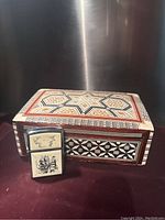 Marquetry box with intricate geometric pattern next to a nautical-themed Zippo lighter