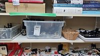 Wide view of shelf with plastic containers holding assorted costume jewelry including necklaces, bracelets and earrings, along with a small basket.