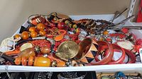 Wide view of white tray with assorted vintage-style orange and red costume jewelry pieces