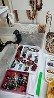 Assorted beadwork necklaces and costume rings in container showing variety of styles and colors