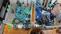 Top-down view of two plastic bins filled with blue and turquoise-tone jewelry