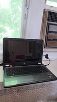 Front view of open HP laptop showing screen, keyboard and surrounding environment