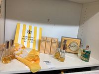 Shelf display showing vintage Giorgio Beverly Hills perfume bottles and boxed sets alongside a yellow and white silk sarong.
