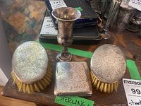 Group shot of two brushes, bud vase, and case on tabletop