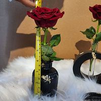 Photo showing black ribbed ceramic vase holding artificial rose with measuring tape showing approx 6 inches tall with visible paint wear.