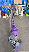 Front and side view of Dyson DC07 upright vacuum cleaner showing purple cyclone assembly and clear dust bin container