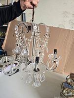 Front angle view of the chandelier showing beaded loops, crystal drops, and five arms with bulb sockets.