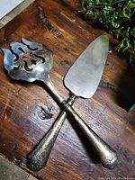 Pair of sterling silver handled cake server and cake fork on a wooden surface, showing length and overall condition.