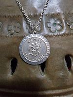 Front view of the round sterling silver Gemini pendant with zodiac engraving and date range, showing design details.