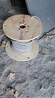 Partial wooden spool of 12 gauge industrial wire coiled neatly, showing the type of wire and condition of the spool.