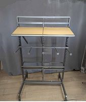 Full view of one garment rack with two wooden shelves and four horizontal display hooks, silver metal frame on wheels.