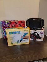 4 3D pens with accessories and 2 VR 360 viewers, three pens in wrapped Christmas boxes, one EVO VR headset, one boxed headset.