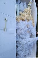 Photo of tightly packed sections of white artificial tree branches, bottom branches have yellowed tips for a more realistic appearance.