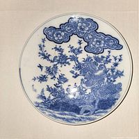 Top view showing detailed blue underglaze painting of birds on flowering branches with clouds near rim.