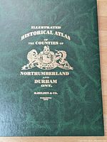 Close-up of green hardcover atlas with embossed gold text and emblem