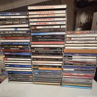 Three stacks of CDs showing various punk and alternative rock artists from the 1990s with visible titles like The Clash, U2, Depeche Mode, Pogues, Love and Rockets.
