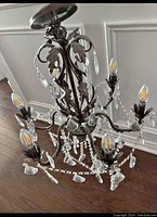 Detailed view of the chandelier showing crystal droplets, candle bulb holders, and ornate metal frame.