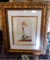 Full view of framed print showing the girl and dog with gold trim mat and carved gold ornate frame.
