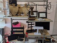Wide shot of shelving with various jewelry displays including burlap busts, black stands, and metal racks.