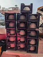 Stack of 16 boxed white porcelain dome light tea light candle holders with embossed designs.