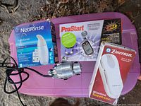 Lot contents on purple container: Neti Rinse box, ProStart remote starter box, vintage silver massager device, Emerson Slimline phone box.