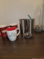 Photo showing the Yeti tumblers, Tim Hortons mugs, and tall glass vase with rocks together