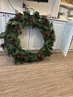 Full front view of the wreath leaning against white cabinetry on a carpeted floor