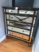 Front view of Arhaus mirrored dresser showing five drawers with distressed mirrored panels and metal knobs.