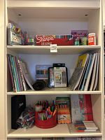 Shelf with assorted pens, markers, and colored pens in containers with a black Sharpie folder