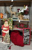 Full view of Christmas decorations on shelving and floor showing main items like Santa figure, reindeer, wreath, candles, and sign.