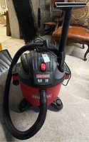 Front view of Craftsman red and black shop vacuum with hose attached, showing brand and specifications.