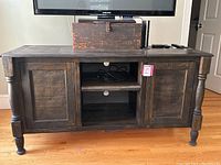 Front view of the entire TV stand with all doors closed and items on top.