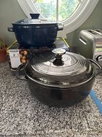 Front view showing black Lodge Dutch oven and blue Emile Henry Dutch oven on box