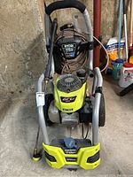 Front three-quarter view on concrete floor showing handle, frame, wheels, engine and pump assembly