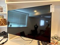 Samsung 42-inch TV angled view on white surface with cables visible underneath, showing the TV's sleek black frame and stand