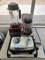 Overview of Vitamix blender, panini press, burger press, boxes of wax paper