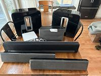 Wide view of two Sonos Sub subwoofers, three soundbars and Play:5 speaker with cables