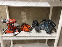 Black & Decker cordless drill, jigsaw and circular saw on a shelf.