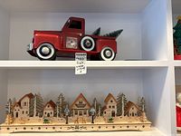 Photo showing full lot setup with the red Christmas truck above the wooden light-up village on shelf.