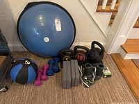 Full view of workout gear including Bosu ball, medicine ball, dumbbells, kettlebells, yoga blocks, and wrist weights.
