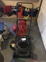 Black & Decker electric lawnmower front view showing the handle with orange extension cord attached and yellow safety bar.