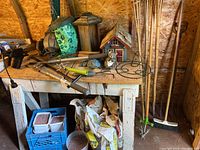 Photo of birdhouses, garden tools on bench, bags of concrete on floor
