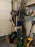 Photo showing large cardboard barrel holding rakes, shovels, and other long-handled gardening tools alongside smaller tools and accessories