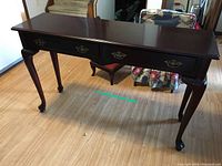 Full view of dark wood hall table showing rectangular shape, two drawers, and cabriole legs.
