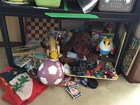 Full lot showing toys, books, stuffed animals, and soccer ball under a table.