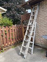 Full view of the 10-foot metal extension ladder leaned against a wall outdoors, showing its length and condition.