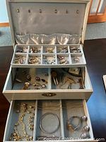 View of overall jewellery box with various jewellery items, watch, and pins organized in compartments