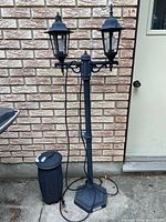 Full view of taller lamp with two lantern lights and shorter single lamp beside it, cords visible on ground