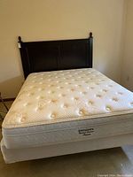 Assembled bed showing dark stained wooden headboard, mattress and metal frame